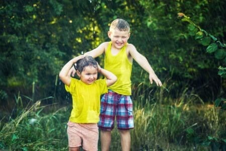 Happy kids playing in the summer rain