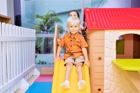 Two little kids playing on an indoor slide