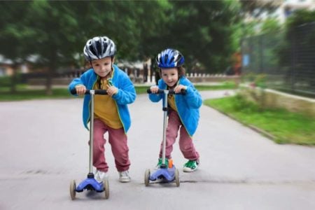 Two little boys racing with their scooters