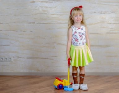 Little girl holding a toy vacuum