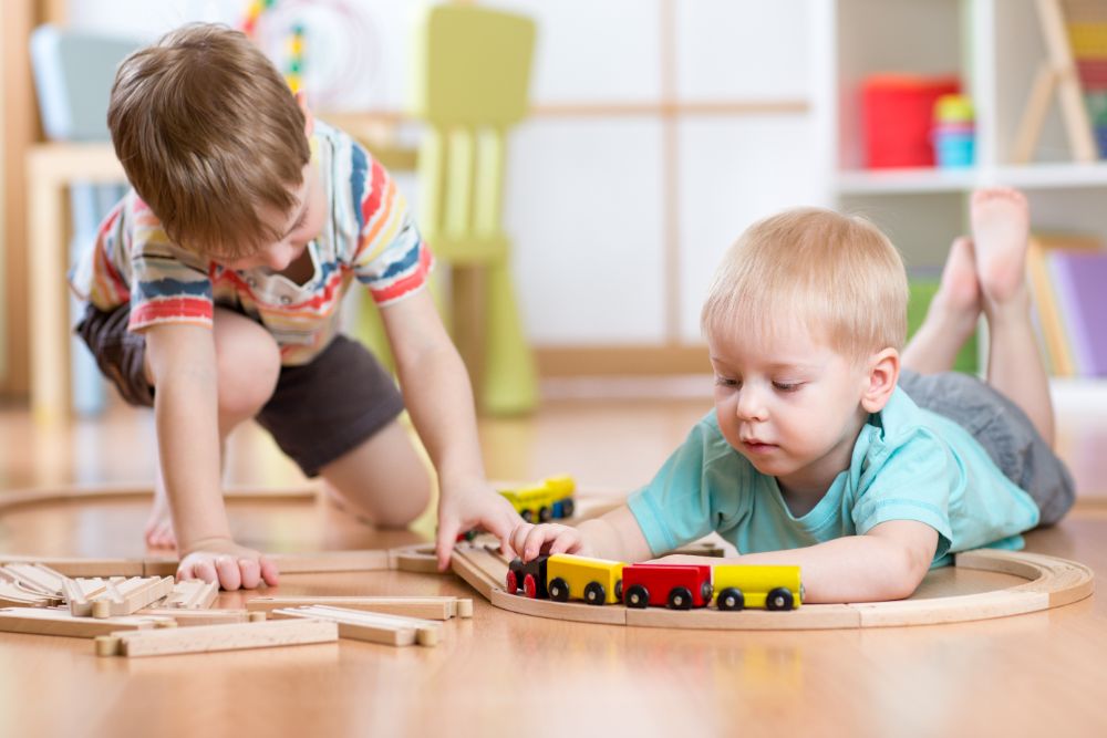 Two little boys playing with wooden train set