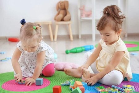 Two toddler girls playing with blocks