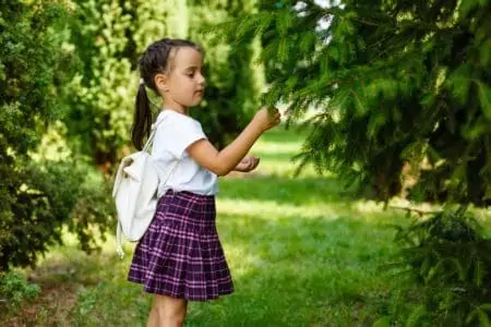 Cute little girl wearing backpack playing in the nature