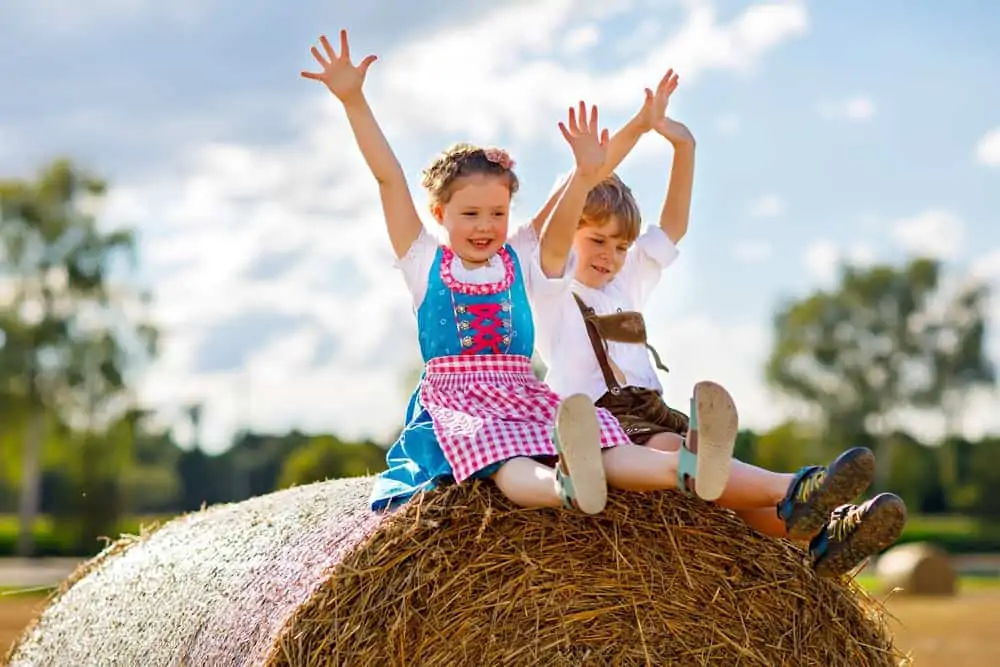 Cute boy and girl wearing traditional costumes while sitting on hay bale