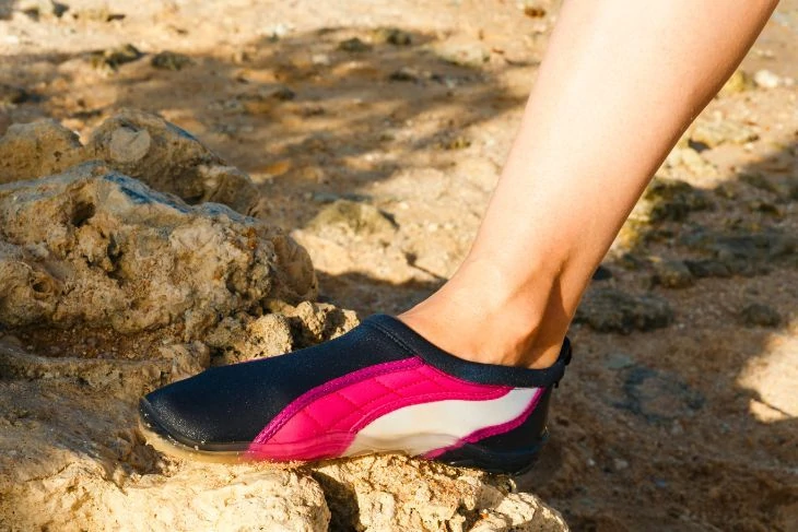 Girl wearing water shoes to protect feet from the_