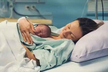 Mom hugging her newborn baby after giving birth in maternity hospital