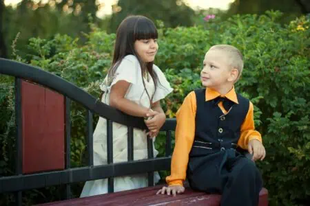 Young boy sitting on the bench while looking at his sibling standing at the back