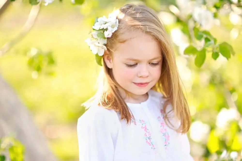 Little girl with a flower hair clip spending time in the garden.